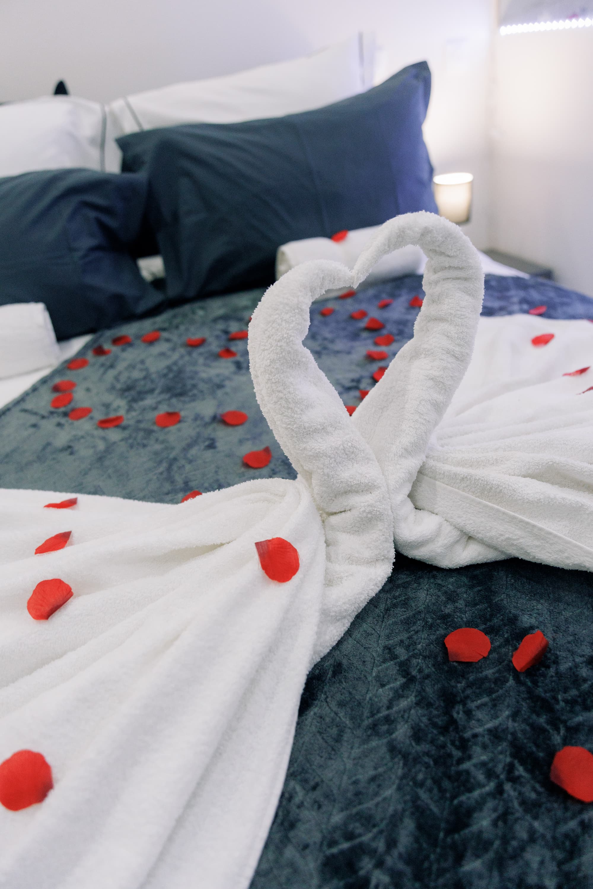Détail romantique : linge délicatement disposé et pétales de roses sur le lit de la suite